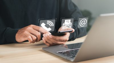 Person using laptop and smartphone at a desk. 